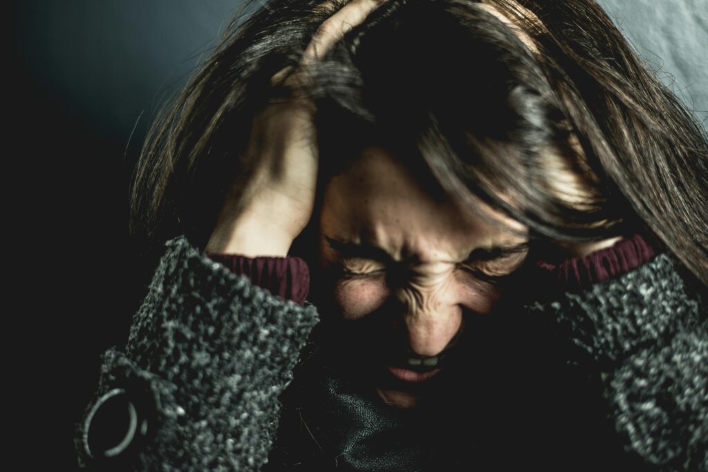 Photo d'une femme en crise d'anxiété avec les mains sur la tête
